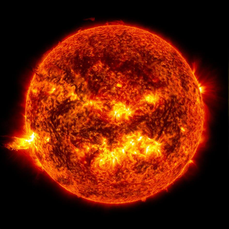 The Sun on a dark background with a solar flare on its bottom left side.