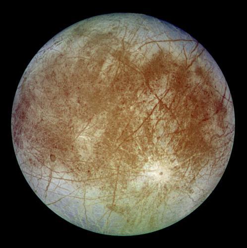 Full globe of Europa, shown as grayish, with orange splotches and straight lines criss-crossing its surface.