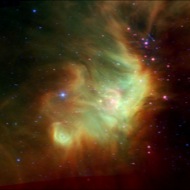 Perseus: In this infrared image of the Perseus Nebula, the green wisps are polycyclic aromatic hydrocarbons, or PAHs. This substance is like black grease on a barbecue grill!