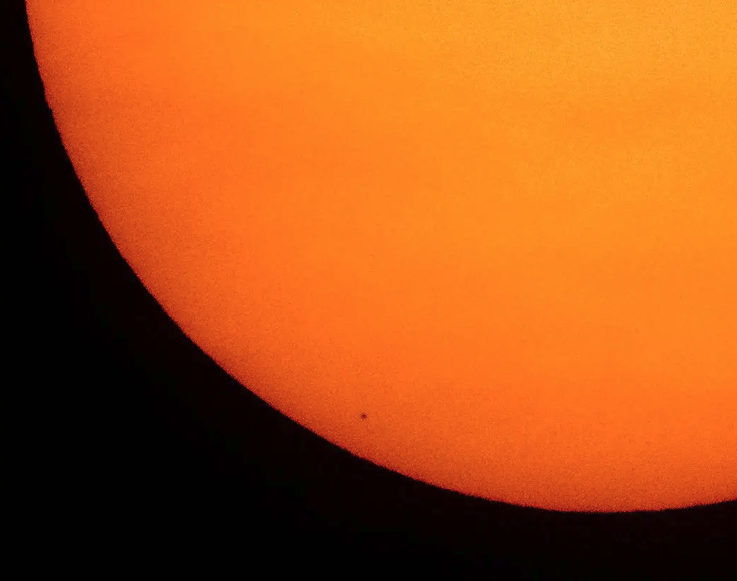 A tiny dot on an orange semicircle shows Mercury as it crosses in front of the Sun.