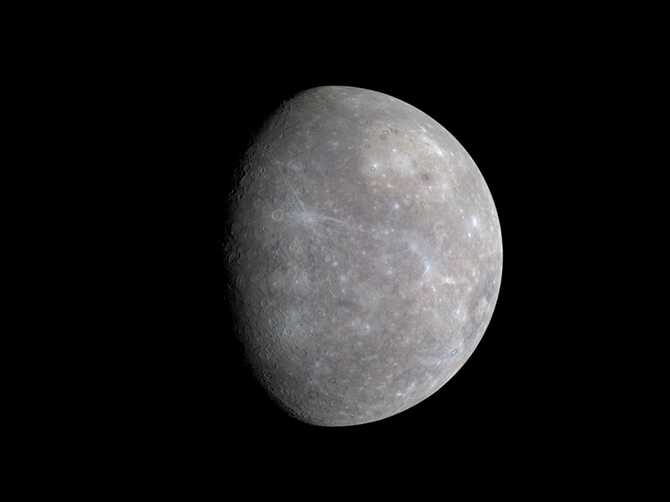 Las diferencias de colores en Mercurio son difíciles de ver a simple vista, pero esta imagen muestra una serie de puntos brillantes con un tinte azulado. Estas manchas revelan información importante sobre el material que forma la superficie del planeta. Estos son cráteres de impacto relativamente recientes. La superficie del planeta es visible sobre un fondo negro.