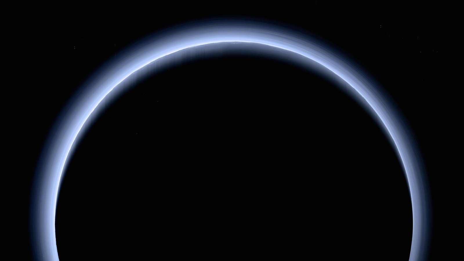 A white halo illuminates Pluto’s horizon against a black foreground and background.
