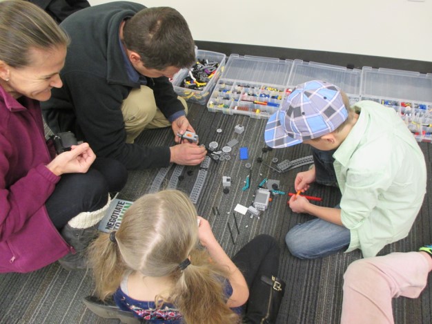 A photo of two children and two adults working with small wheels and blocks