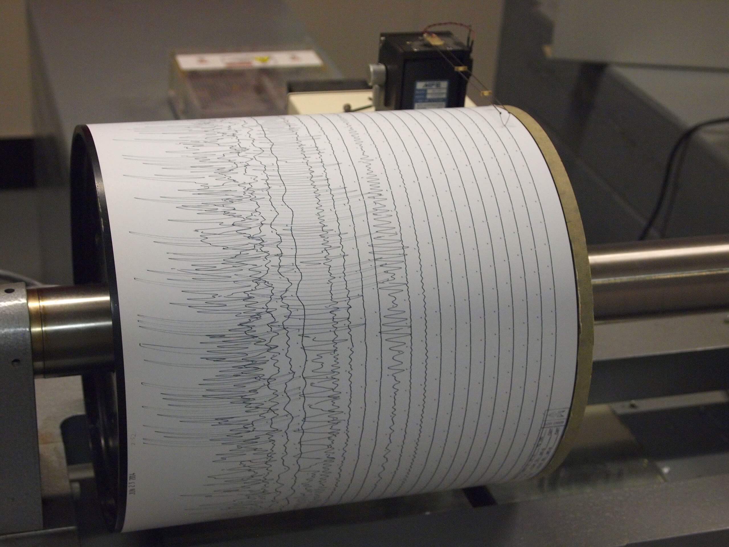 地震計が地震波を一連のジグザグ線として記録している写真