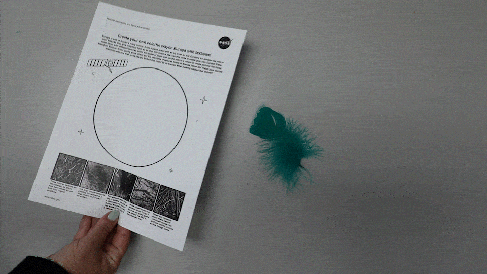 Gif of hand placing Europa activity page over a teal feather.