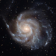 picture of the pinwheel galaxy with visible light so the pinwheel shape appears in tans, purples, and greys.