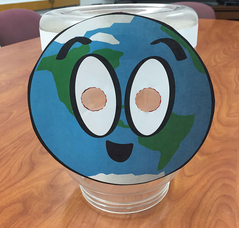 a paper planet mask displayed on a clear cylinder