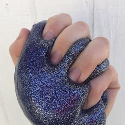 A hand squeezing sparkly slime.