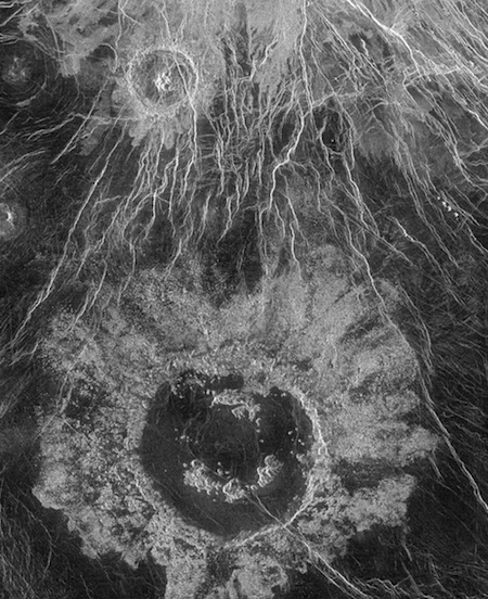una foto de un gran cráter y muchas grietas blancas en la superficie