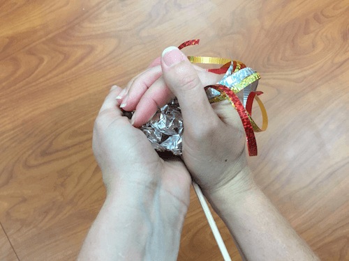 a photo of hands cupping the tin foil together into a ball