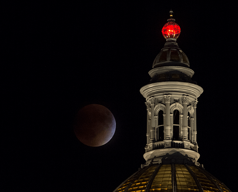 Image of a supermoon total lunar eclipse behind the Colorado State Capitol building.