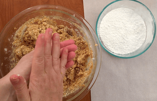 a person rolls the cookie dough into a ball with her hands.