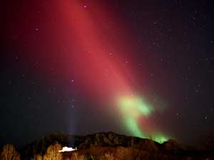 El cielo nocturno brilla con una luz de color rojo y verde.