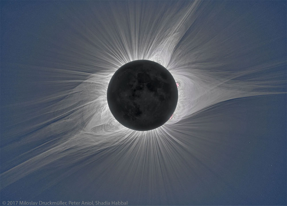 At the center of the image, the Moon blocks the Sun during a total solar eclipse. The Sun’s wispy upper atmosphere can be seen around the edge of the Moon.