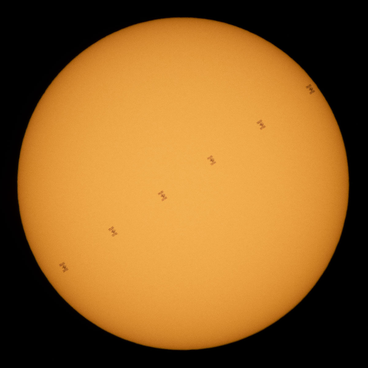 The International Space Station can be seen transiting an orange Sun in this combined photo.