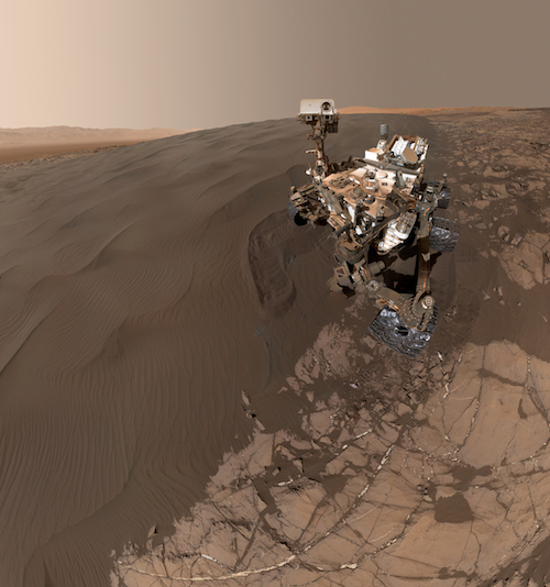 An image of the Curiosity rover taking a self-portrait on a Martian sand dune.