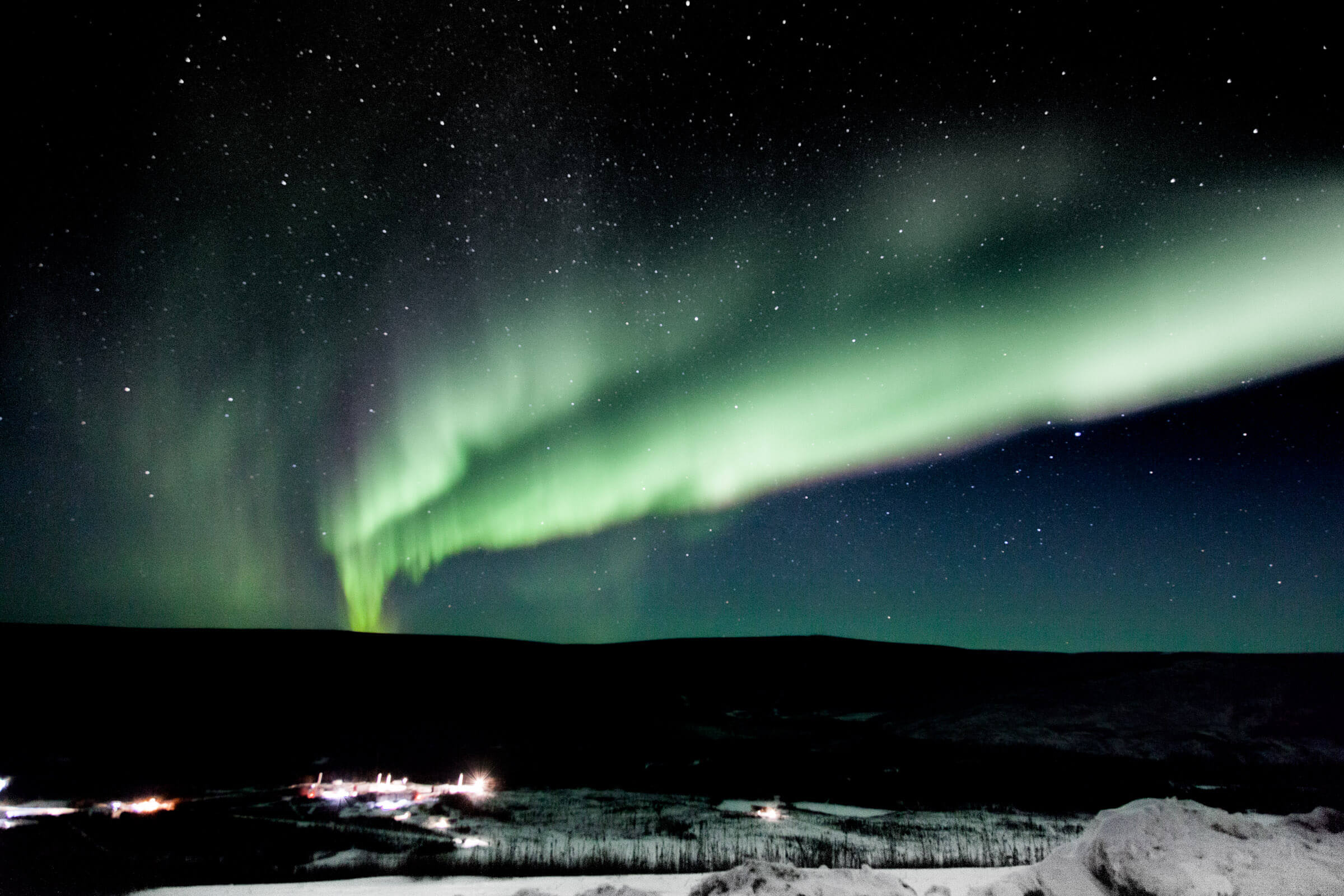 A photograph of green aurora against a dark night sky