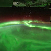 a photograph of green auroras over the Earth