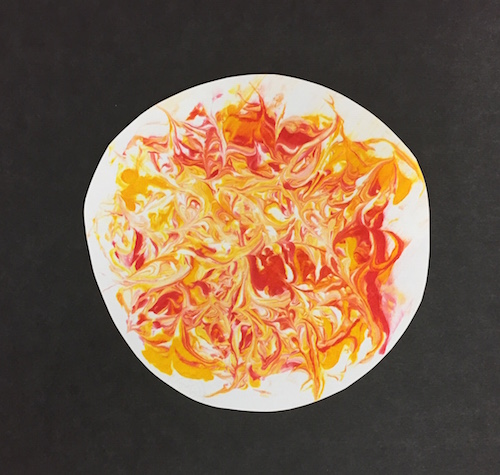 the cut out Sun shape with swirls of food coloring mounted on a black piece of paper