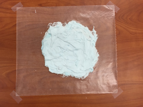 a photo of wax paper taped to a table with a big glob of shaving cream