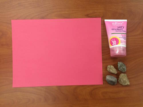 a photo of construction paper, sunscreen, and rocks on a table top